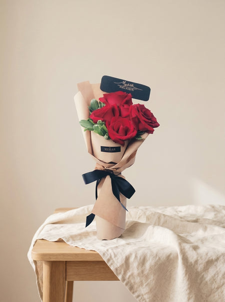 Éloise Sand bouquet of six red roses in sand-toned wrapping with a black ribbon