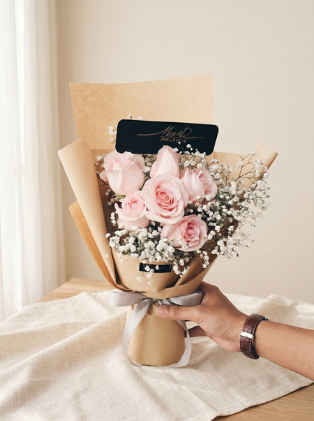Celeste Blush bouquet of six pink roses with white baby's breath in beige wrapping